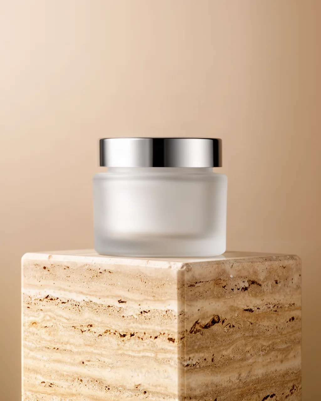 Unlabeled frosted glass cream jar on a travertine pedestal, studio packshot